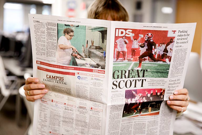 A person reads a newspaper.